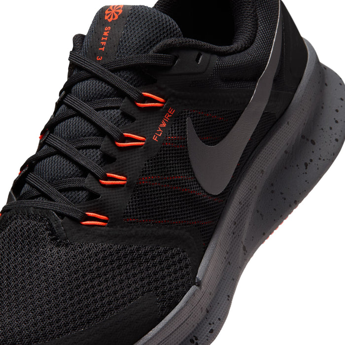 Men's black running shoe close-up, Flywire-style lacing with orange-red lines