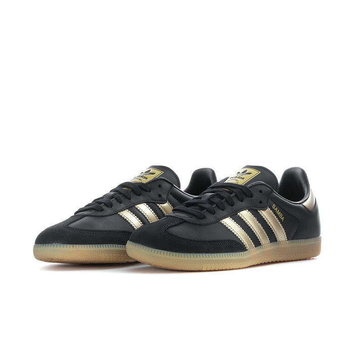 Samba OG women's sneakers angled front view, black leather with gold stripes and gum sole