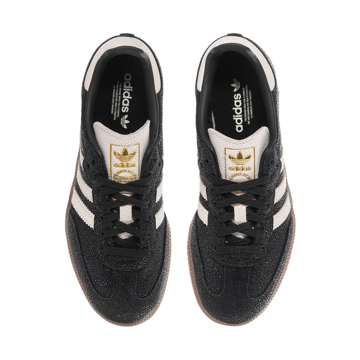 Black Adidas Samba OG sneakers with gold tongue patch, white stripes, and lace-up front