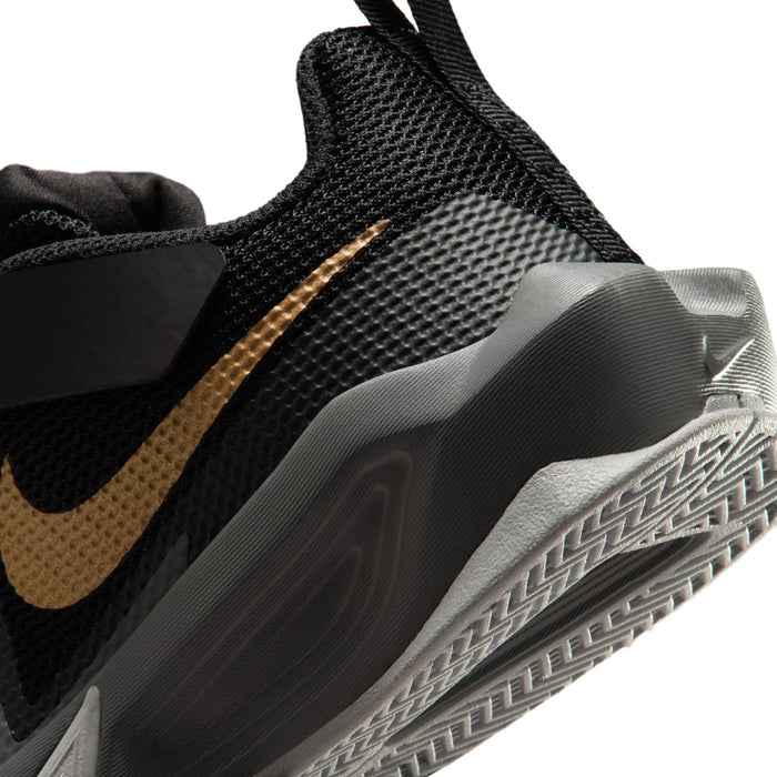 Kids black sneaker close-up with gold swoosh, mesh texture, and gray rubber outsole