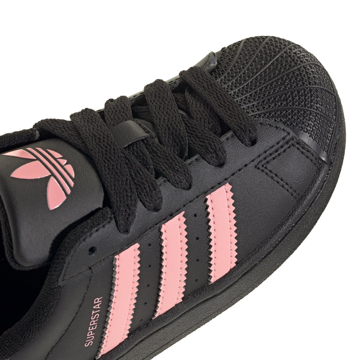 Kids' adidas sneakers, close-up of black upper with pink triple stripes