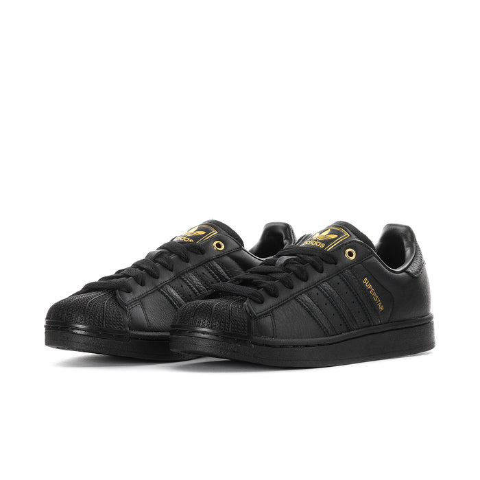 Men's black Adidas sneakers, side view with three gold stripes and lace-up front.