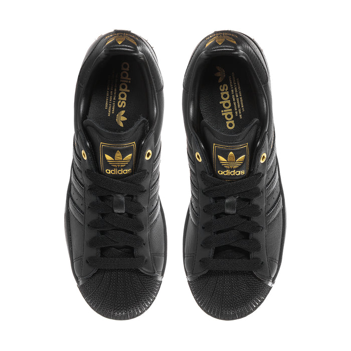Men's black Adidas sneakers, inside view of tongue and heel with gold logo detail.