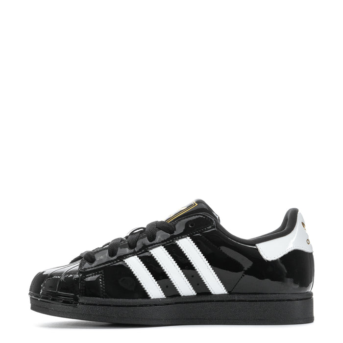 Women’s black patent leather low-top sneaker with white side stripes and lace-up closure
