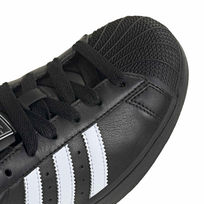 Close-up of women’s adidas Superstar II black leather upper with white triple stripes