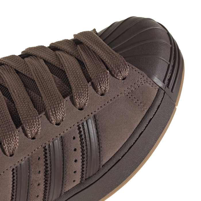 Brown suede sneaker upper close-up with lace eyelets and three stripe panels