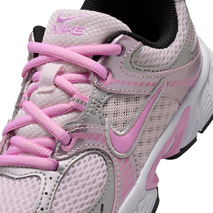 Close-up of kids sneaker side with pink laces, mesh panels, and stitched overlays