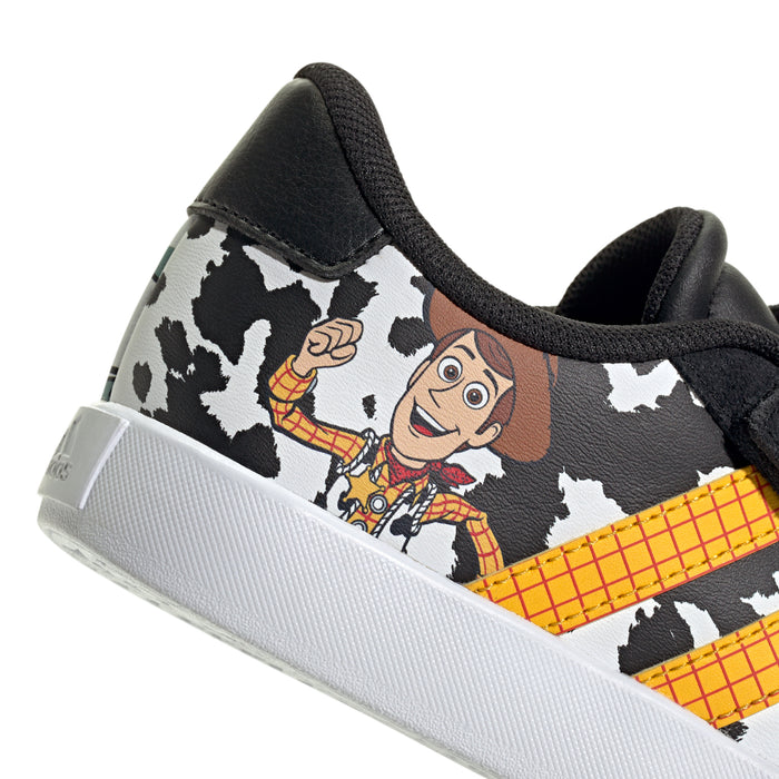 Kids' sneaker close-up: cow-print upper with character artwork, lace-up front, black sole