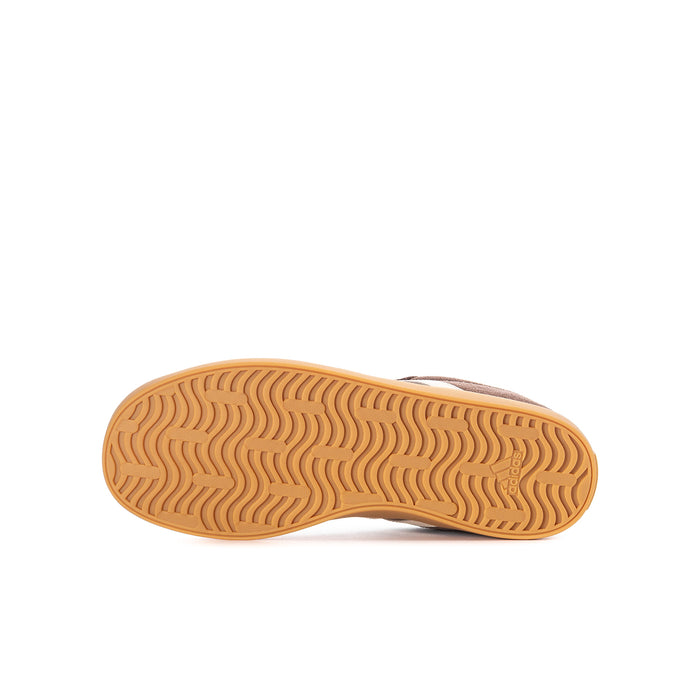 Youth sneaker outsole, gum-brown tread with wavy traction pattern.