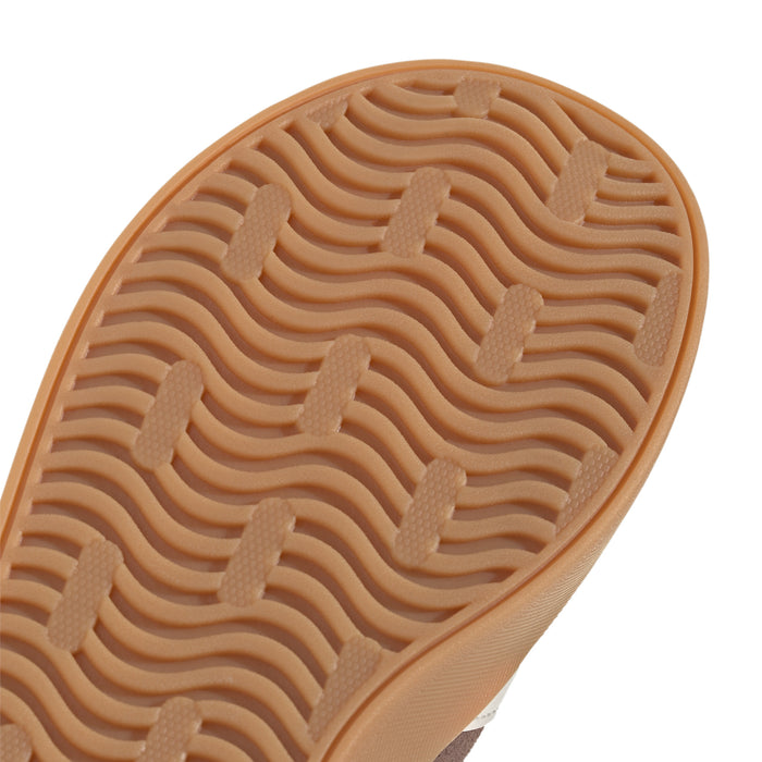 Close-up youth outsole tread, gum-brown with raised wave and herringbone-like grips.